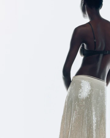 Model seen from behind wearing a sequined skirt against a bright white background for Samsoee Samsoee