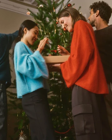 Group of four models decorating a Christmas tree in a living room setting for Banana Republic holiday campaign.