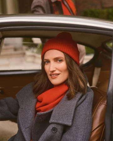 Woman wearing a grey coat and red beanie sitting in a car driver seat