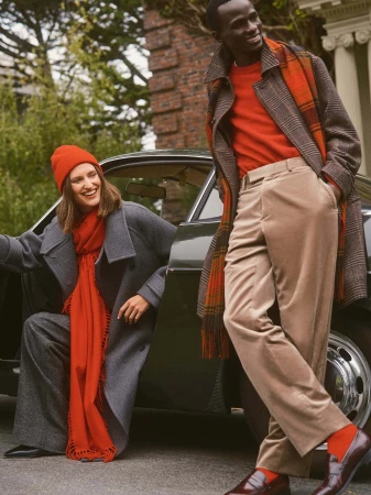 Two models posing near a vintage car wearing winter coats, red scarves, and beanies in San Francisco.