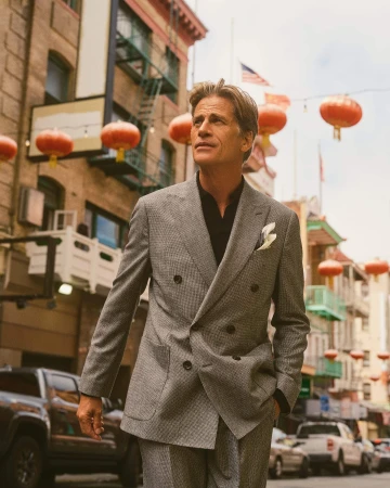 Man wearing a grey double breasted houndstooth suit standing on a city street decorated with red lanterns