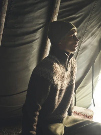 Man wearing a patterned wool sweater and beanie inside a tent for Loro Piana Après Ski Fall 2024 campaign