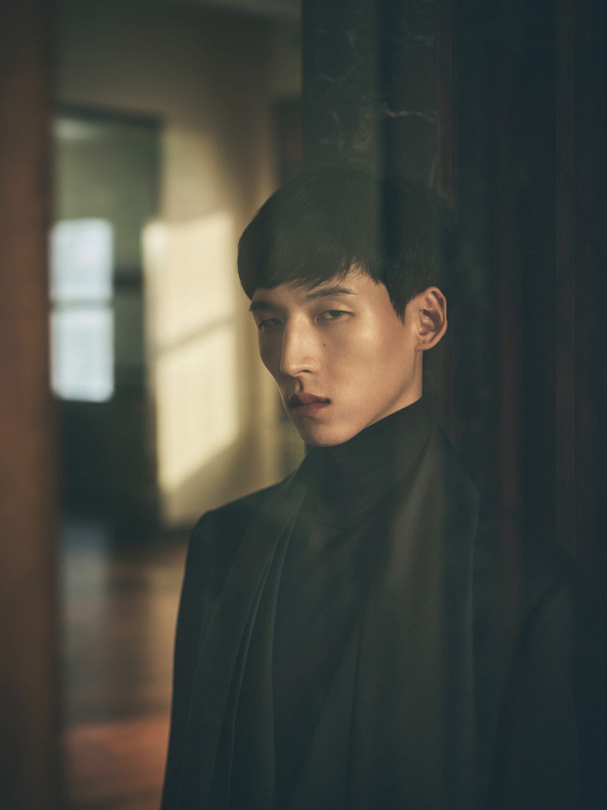 Man wearing a dark turtleneck and jacket in an interior setting photographed by Annemarieke Van Drimmelen for Loro Piana