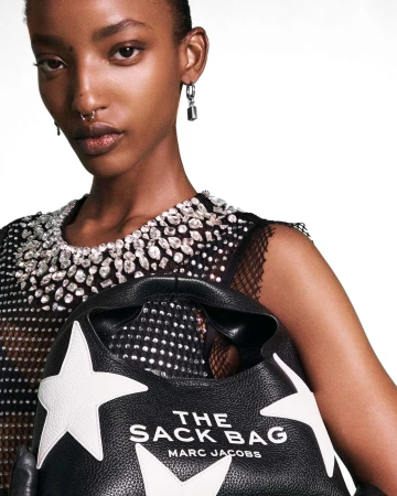 Close-up portrait of a woman holding The Sack Bag by Marc Jacobs against a seamless white background