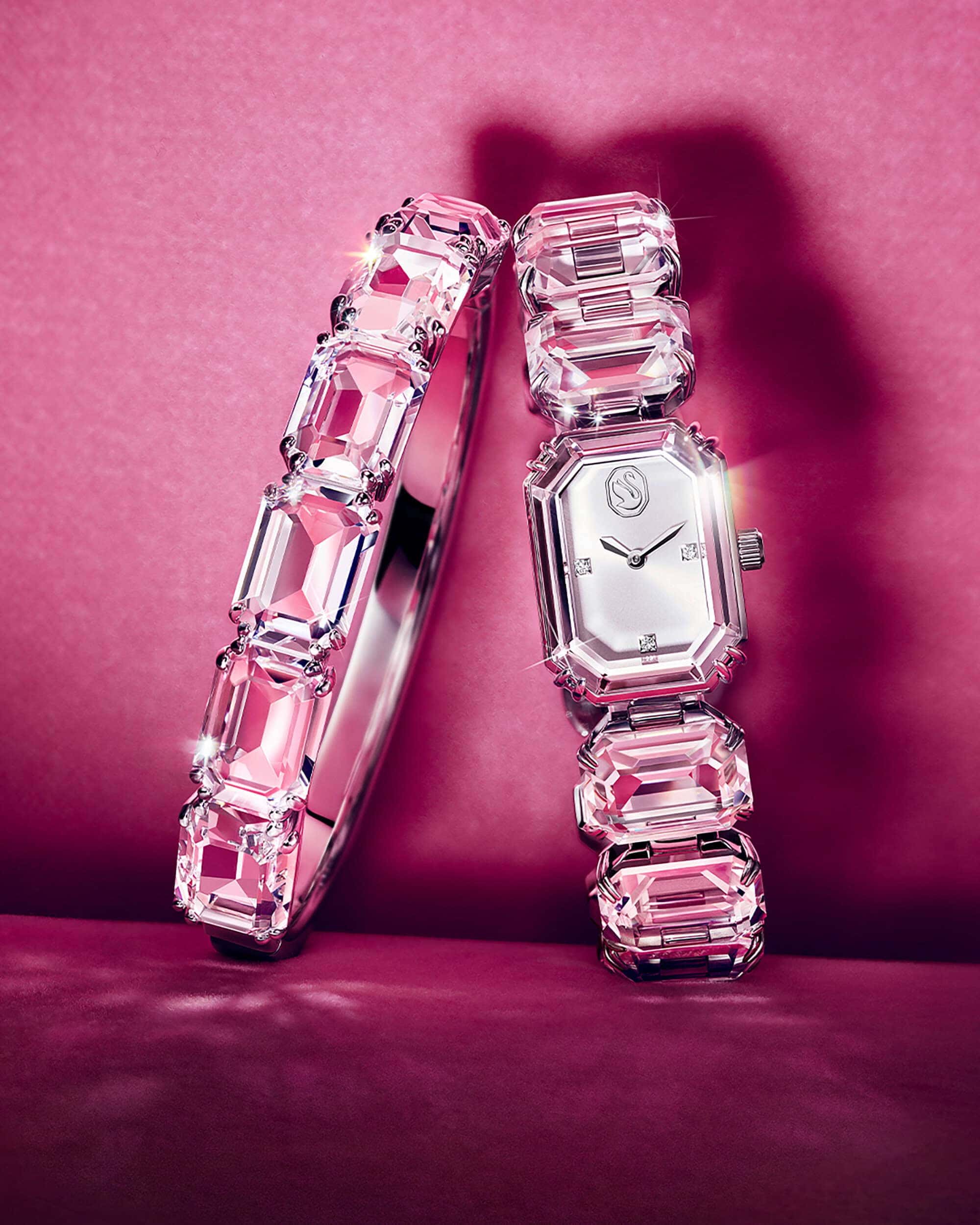 Crystal bangle bracelet and matching crystal watch standing on a vibrant pink surface with dramatic lighting