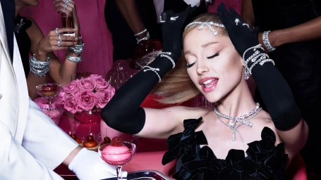 Ariana Grande wearing diamond jewellery, black opera gloves, and a black dress in a pink setting for Swarovski Holiday 2024 campaign