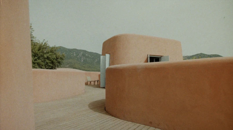 Curved terracotta walls and wooden decking under an overcast sky for Adriana Degreas Spring 2025 campaign.