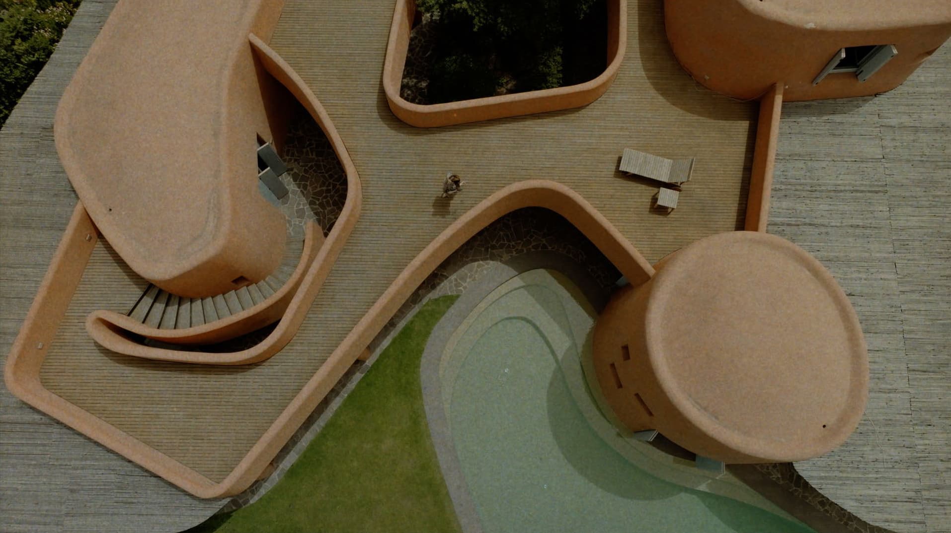 Aerial view of modern terracotta architecture with organic curved walls and a swimming pool for Adriana Degreas