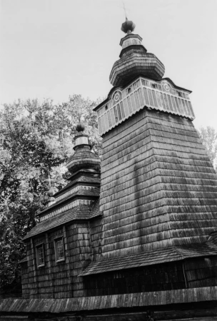 Monochrome architectural photograph of a traditional wooden church with tiered cupolas under an overcast sky.