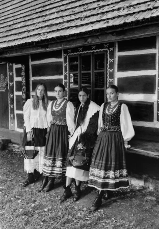 Four models in traditional folk-inspired apparel standing outside a dark wooden cabin for the Chylak Fall 2024 campaign.