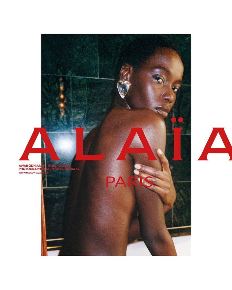 Model wearing a large heart-shaped earring posing in front of a dark tiled wall for Alaia Fall 2024 campaign