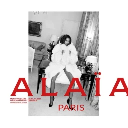 Black and white portrait of a model wearing a plush white coat seated indoors with red ALAÏA text overlaid.