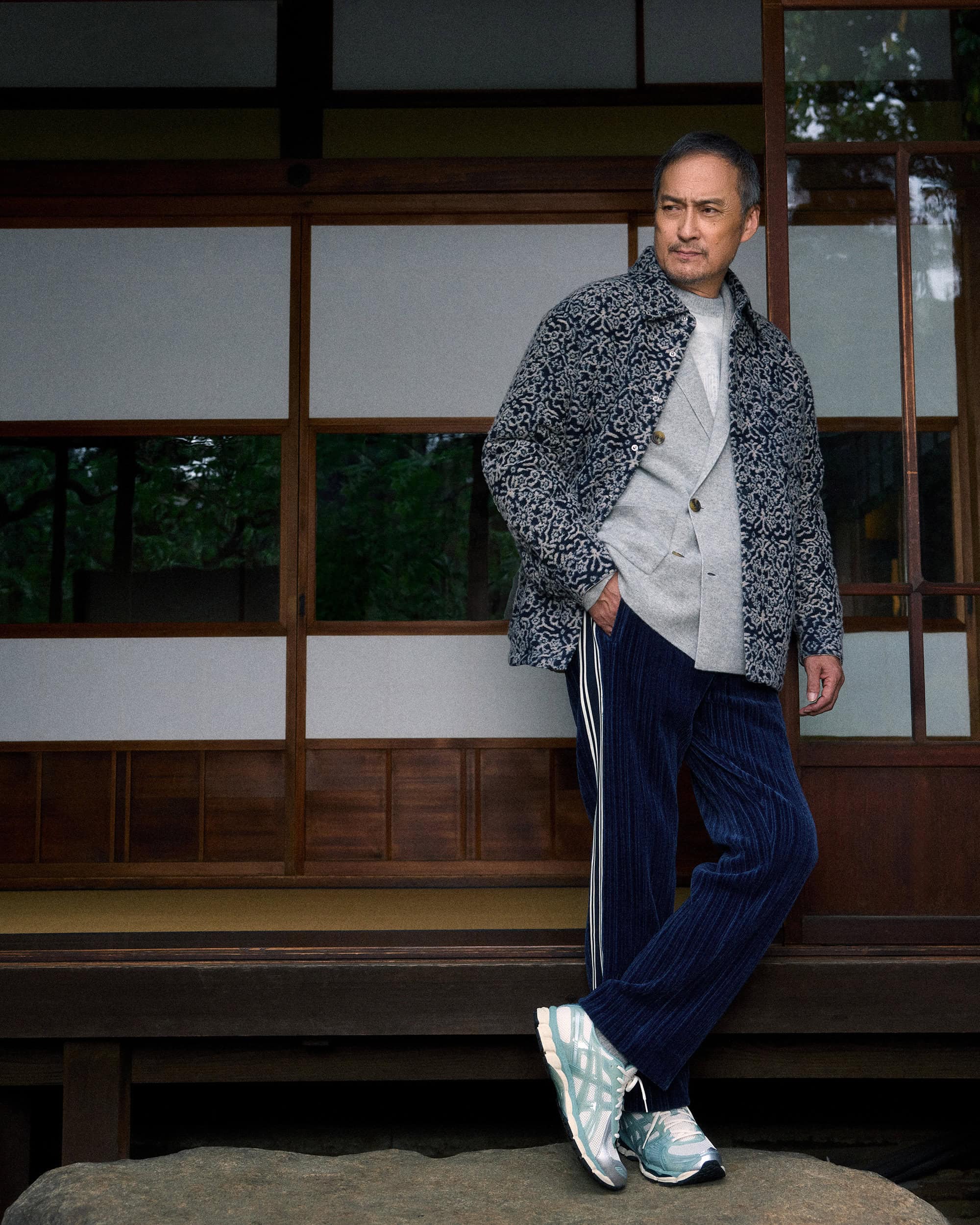 Ken Watanabe posing in a patterned jacket and navy blue trousers in front of traditional shoji screens for Kith.