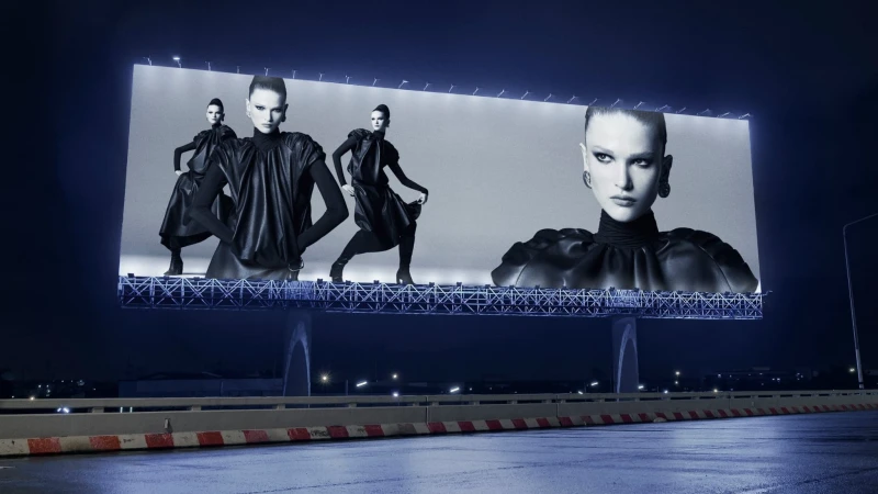Large illuminated outdoor billboard at night displaying black and white fashion campaign imagery for Zara.