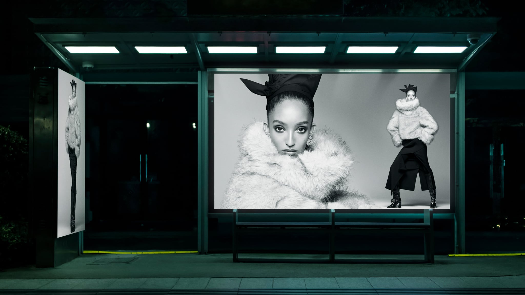 Illuminated bus shelter at night displaying black and white fashion advertisements for Zara starring Mona Tougaard