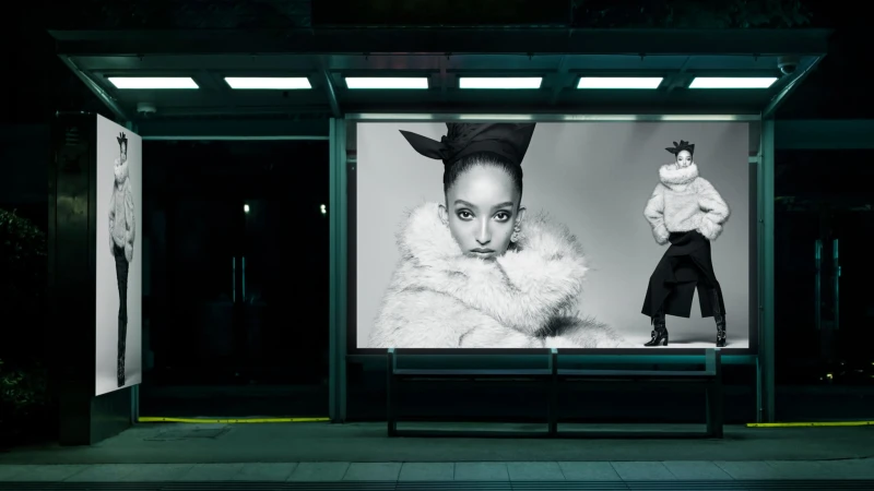 Illuminated bus shelter at night displaying black and white fashion advertisements for Zara starring Mona Tougaard