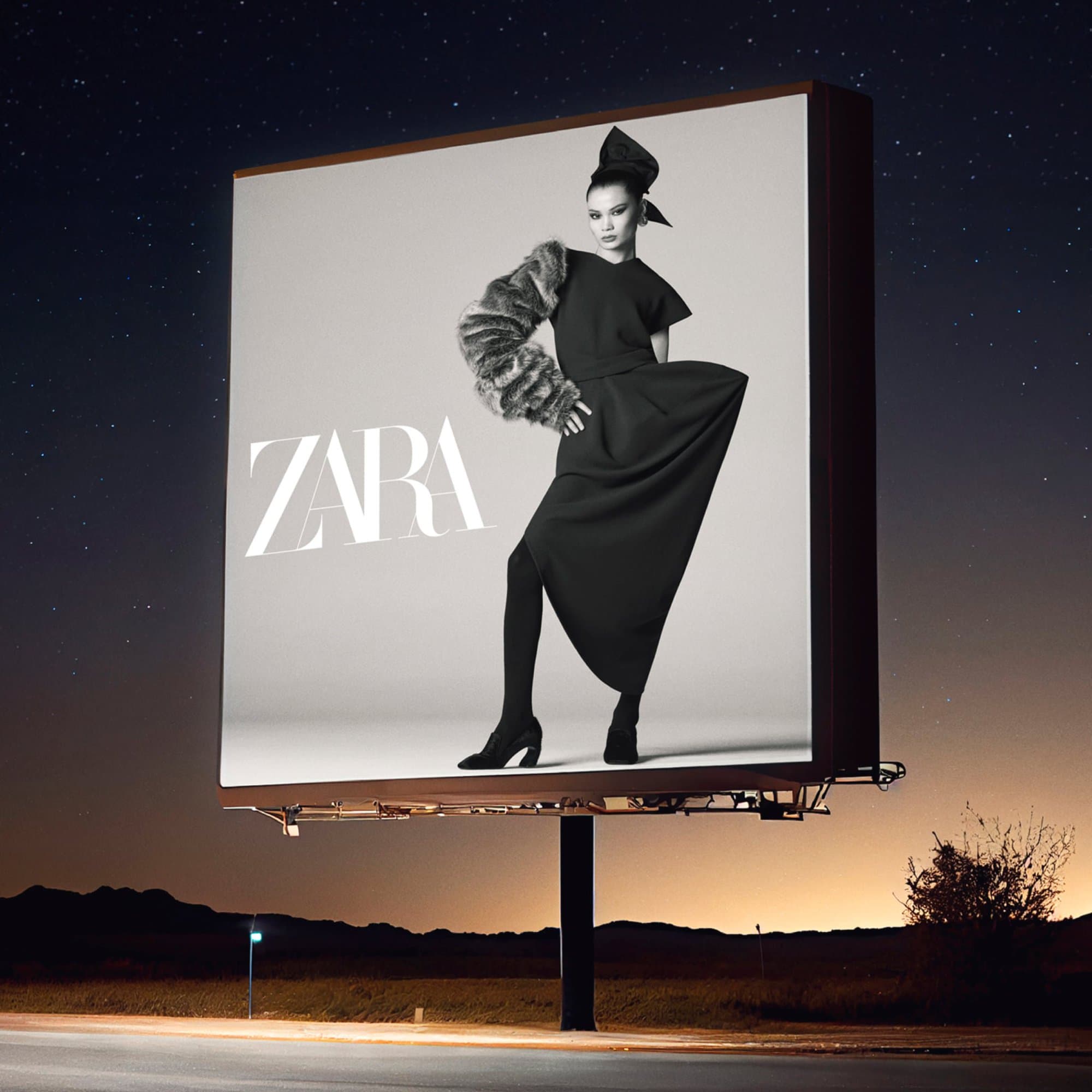 An illuminated outdoor billboard displaying a Zara fashion campaign ad against a dark night sky.