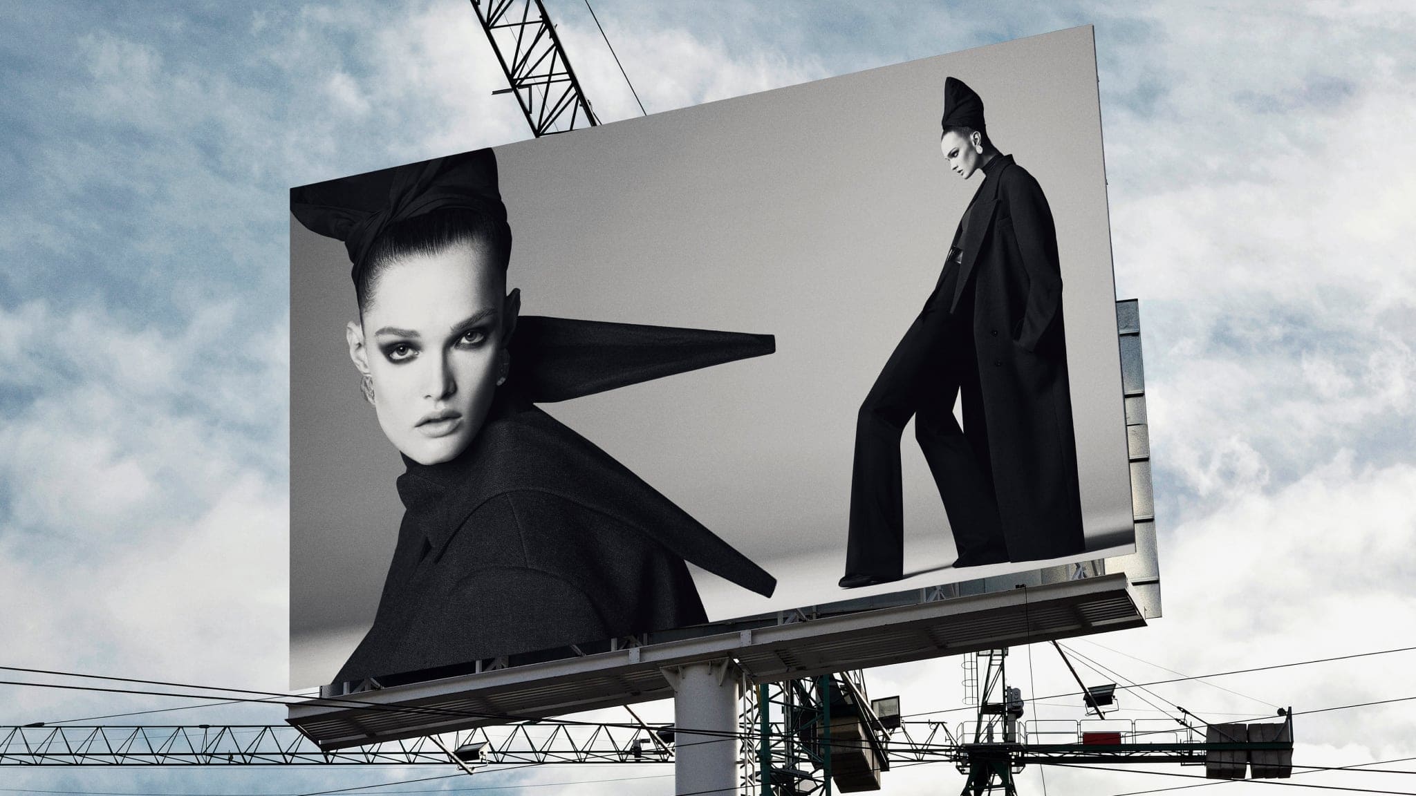 Monochrome billboard showing a close-up portrait and a full-length shot of a model in black fashion attire