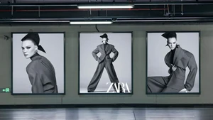 Three large backlit fashion billboard posters displaying a model in a tailored suit in a concrete parking garage