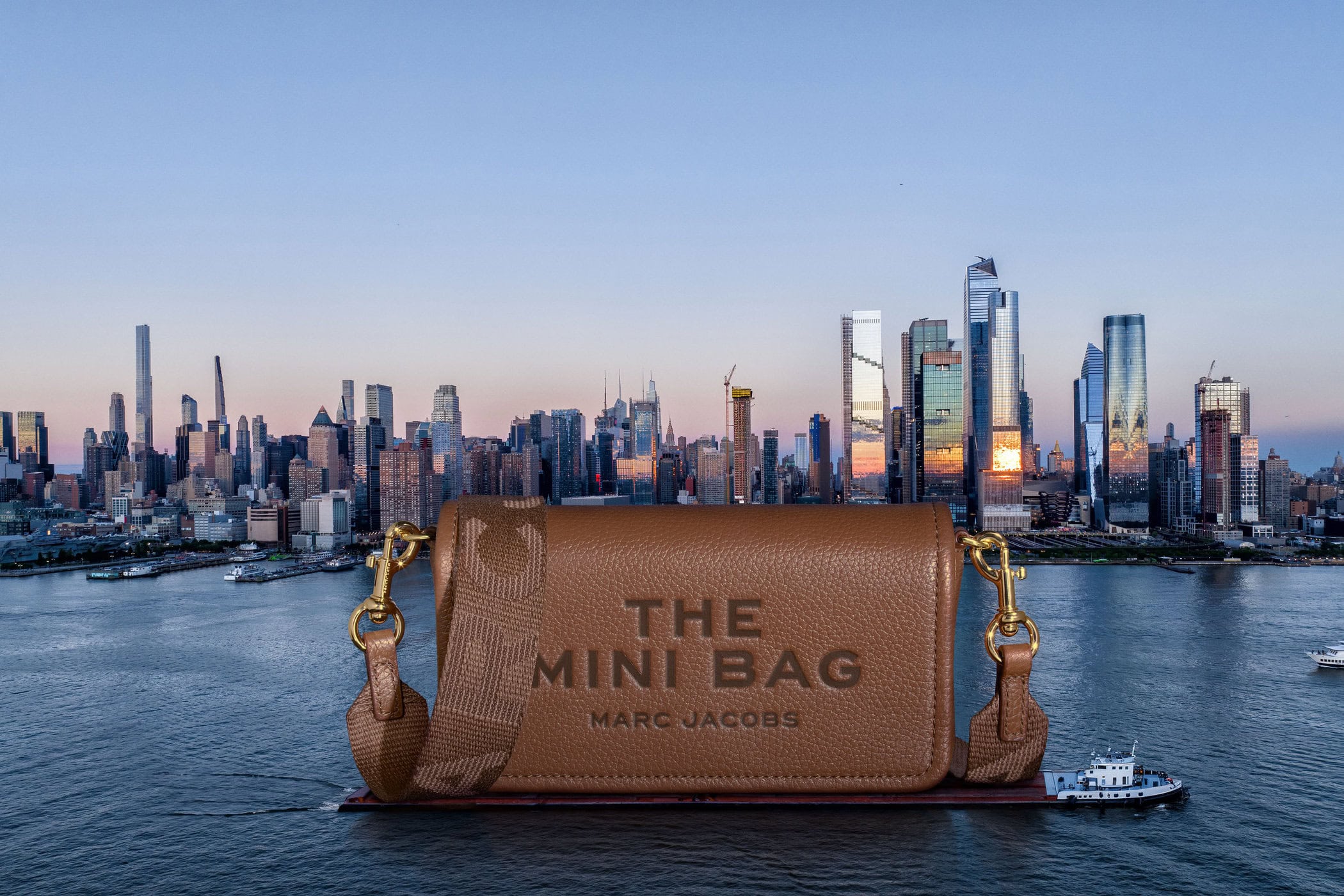 Tan leather Marc Jacobs mini handbag displayed against a cityscape and waterfront backdrop