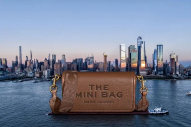 Tan leather Marc Jacobs mini handbag displayed against a cityscape and waterfront backdrop
