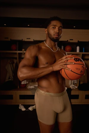 Basketball player Donovan Mitchell holding a basketball in a locker room for SKIMS