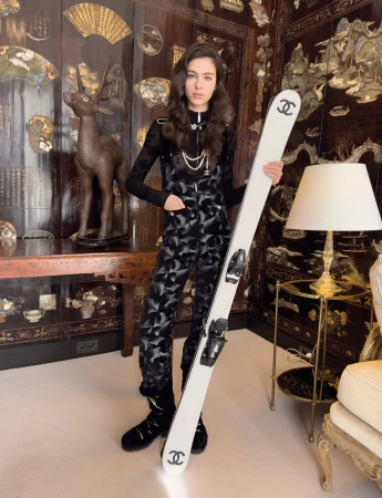 Model Loli Bahia holding white Chanel skis in a decorative room for the Coco Neige 2024 campaign, photographed by Juergen Teller.