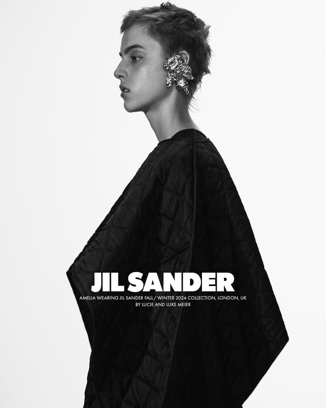 Model in profile wearing a quilted black top and a large metallic ear cuff against a plain white background