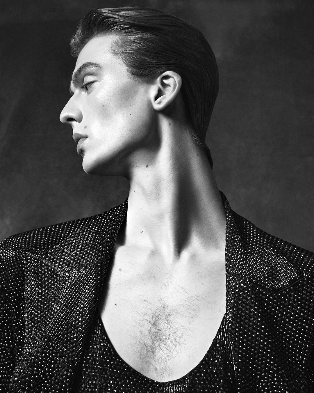 Monochrome portrait of male model Leon Dame in profile wearing an embellished dark jacket for Dolce & Gabbana fall 2024 campaign