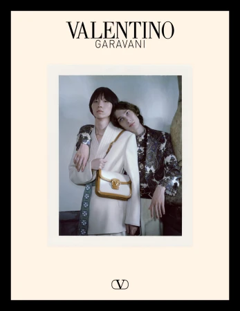 Two models posing together against a neutral wall for Valentino Avant les Débuts campaign, holding a white leather handbag