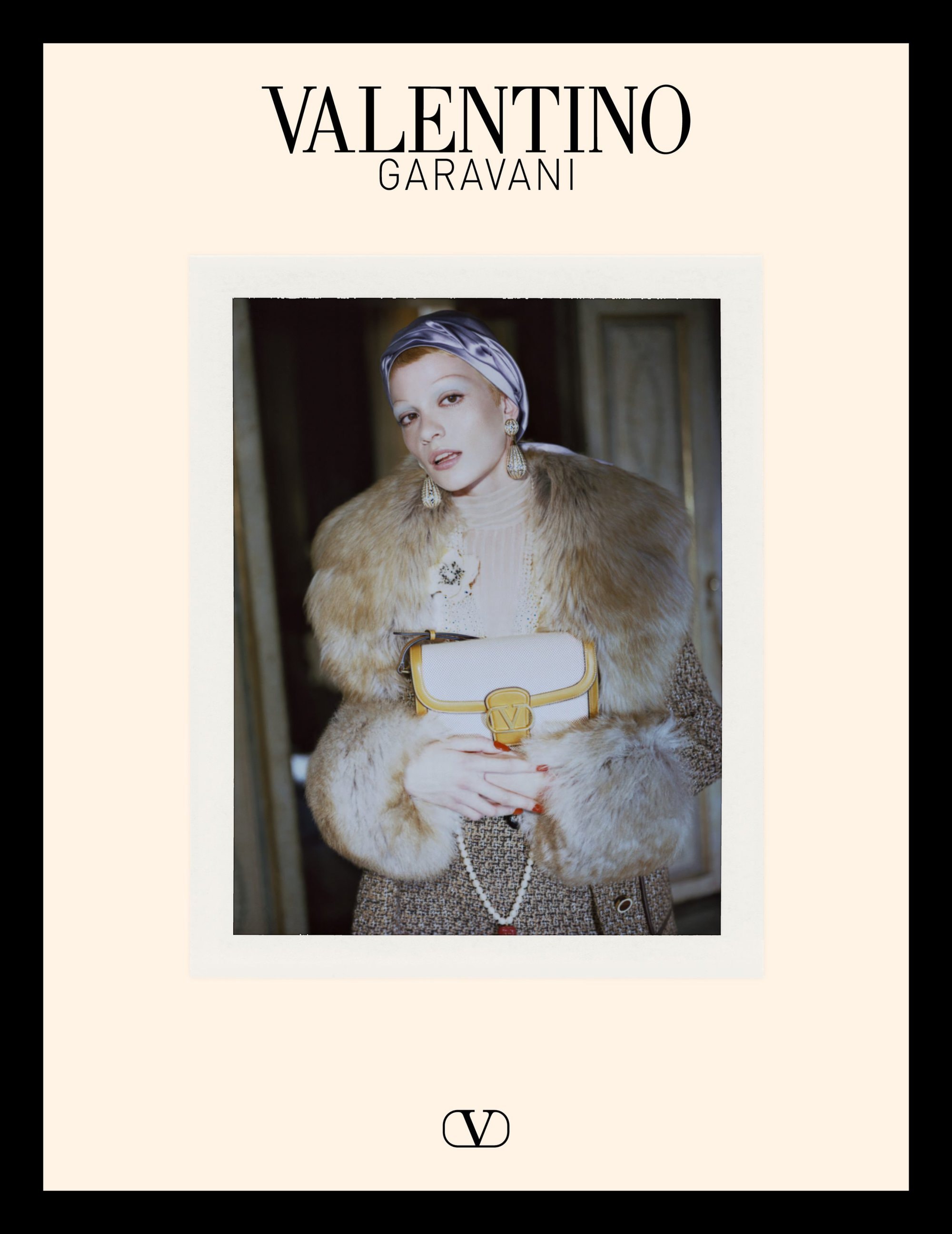 Model in fur collar coat holding white handbag with silk head wrap for Valentino campaign