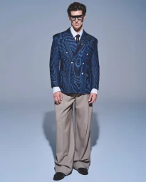 Model wearing a blue double-breasted patterned blazer and wide-leg trousers against a grey studio backdrop