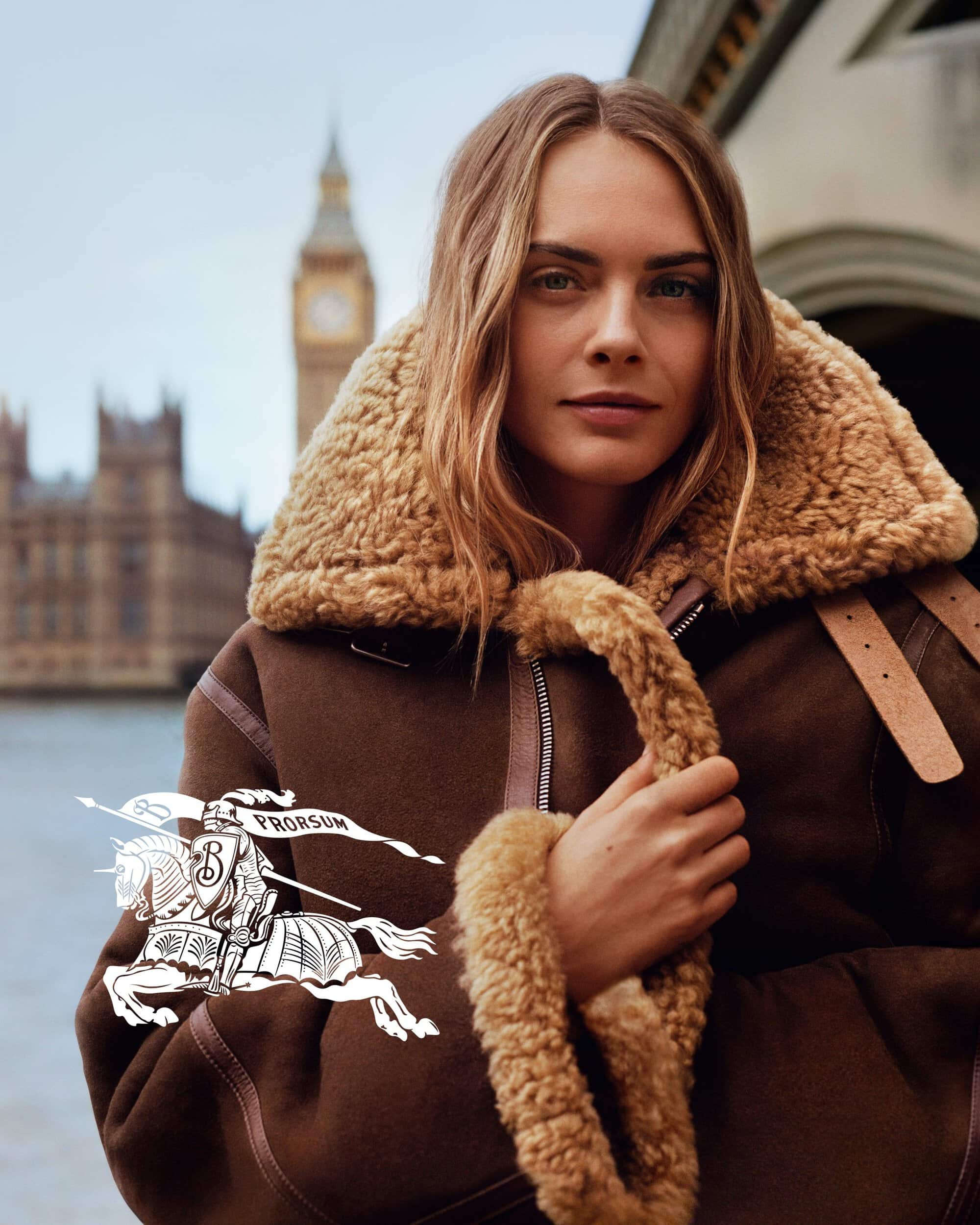 Cara Delevingne wearing a brown shearling aviator jacket outdoors in London with Big Ben in the background.