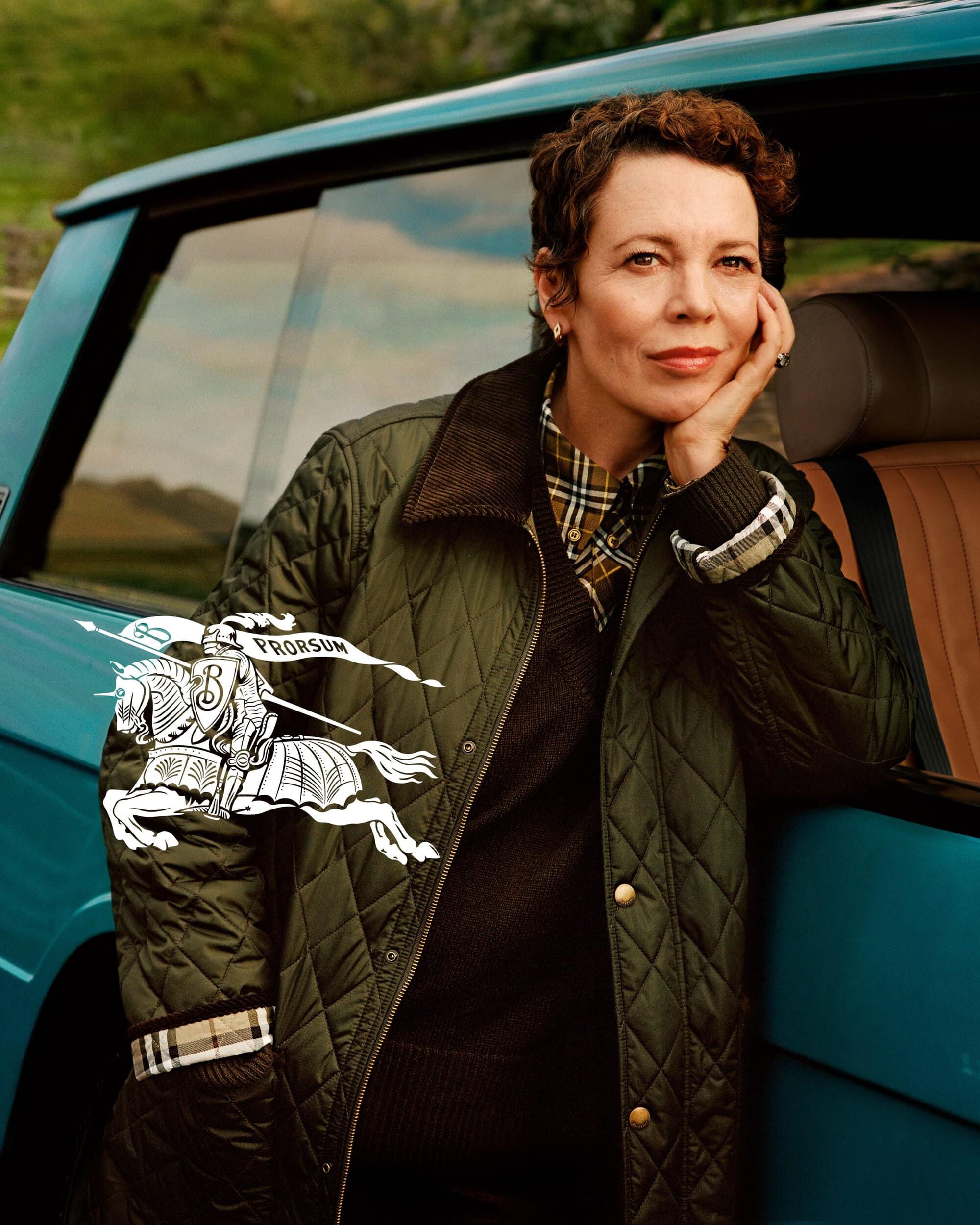 Olivia Colman wearing a quilted green jacket leaning against a turquoise car for the Burberry 2024 campaign