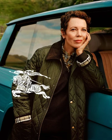 Olivia Colman wearing a quilted green jacket leaning against a turquoise car for the Burberry 2024 campaign