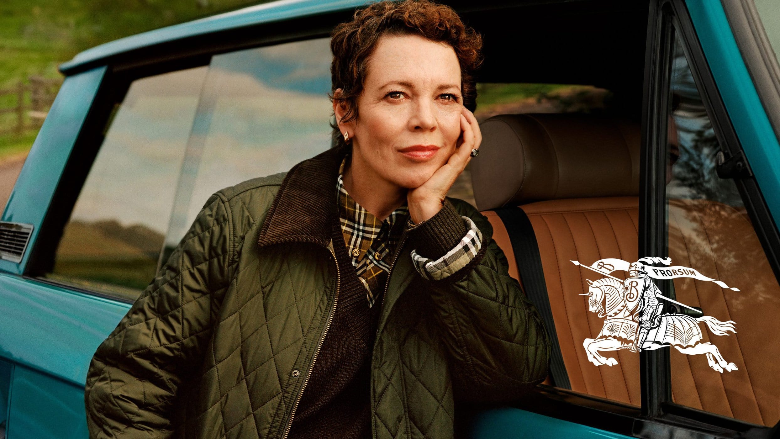 Olivia Colman wearing a quilted olive green jacket leaning against a turquoise car for Burberry