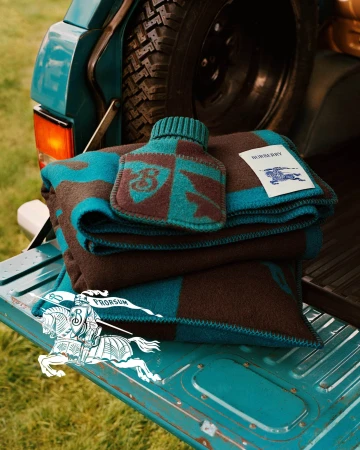 Folded blue and brown patterned blanket with matching hot water bottle in the open tailgate of a vehicle