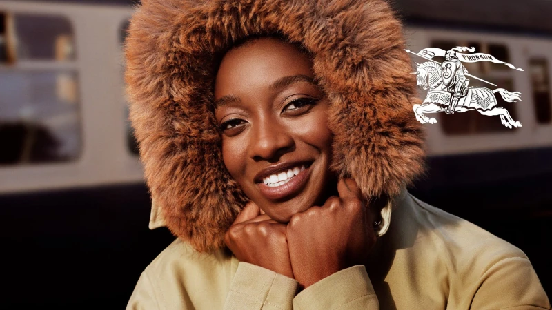 Close-up portrait of Little Simz wearing a fur-lined hood and tan jacket for Burberry, photographed by Alasdair McLellan.