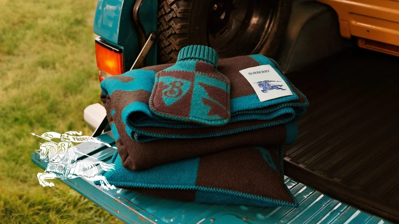 Folded blue and brown wool blanket with a matching hot water bottle resting on the open tailgate of a teal truck