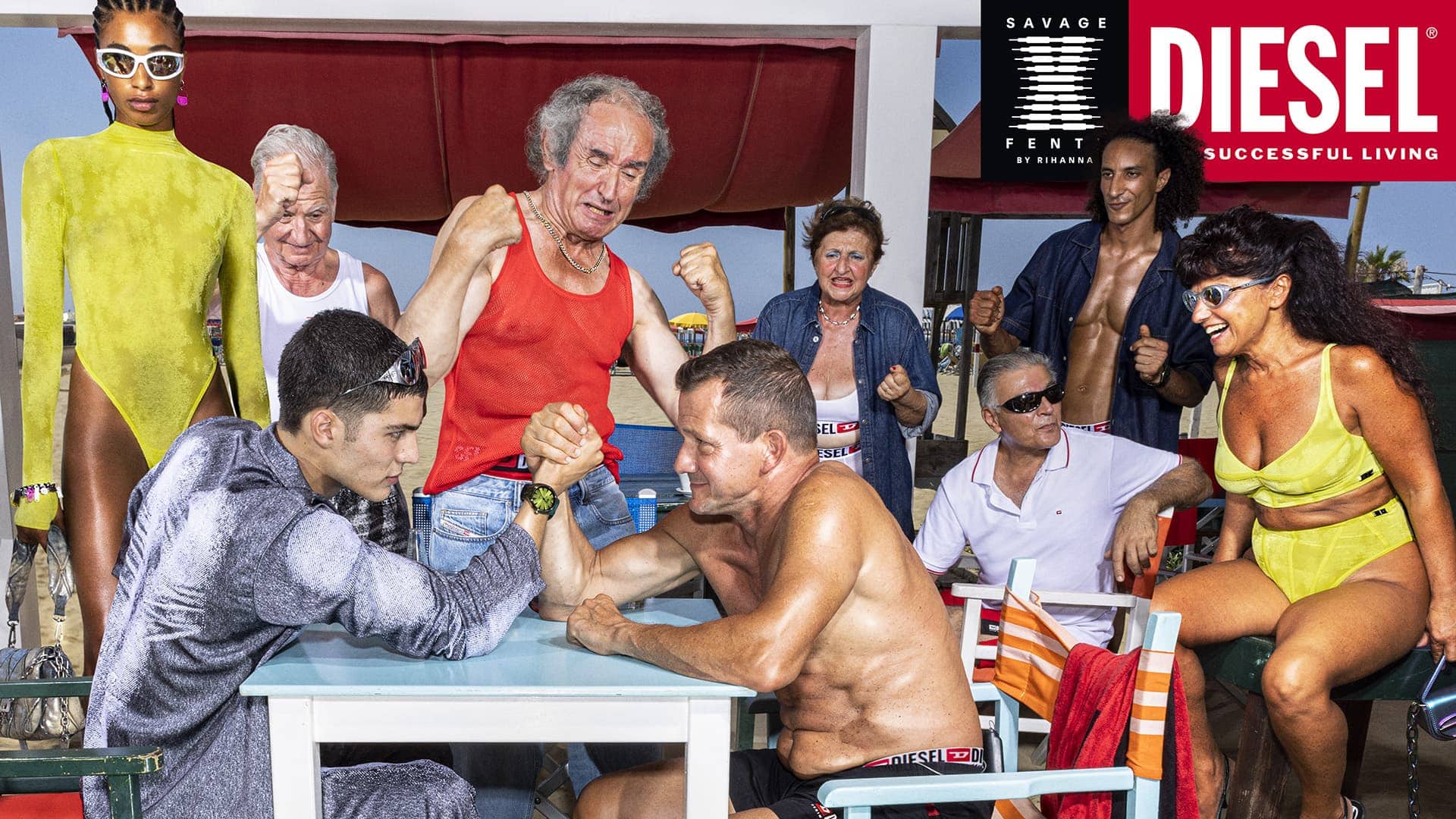 Group of diverse models and older adults at an outdoor table arm wrestling in a beach setting for Diesel x Savage X Fenty campaign.