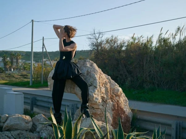 Model Karolin Wolter posing on a rock wearing a black outfit for Alexandre Vauthier spring 2025 campaign
