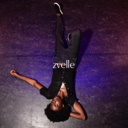 Model lying upside down on a dark textured surface wearing black trousers and a black button-down shirt for Zvelle