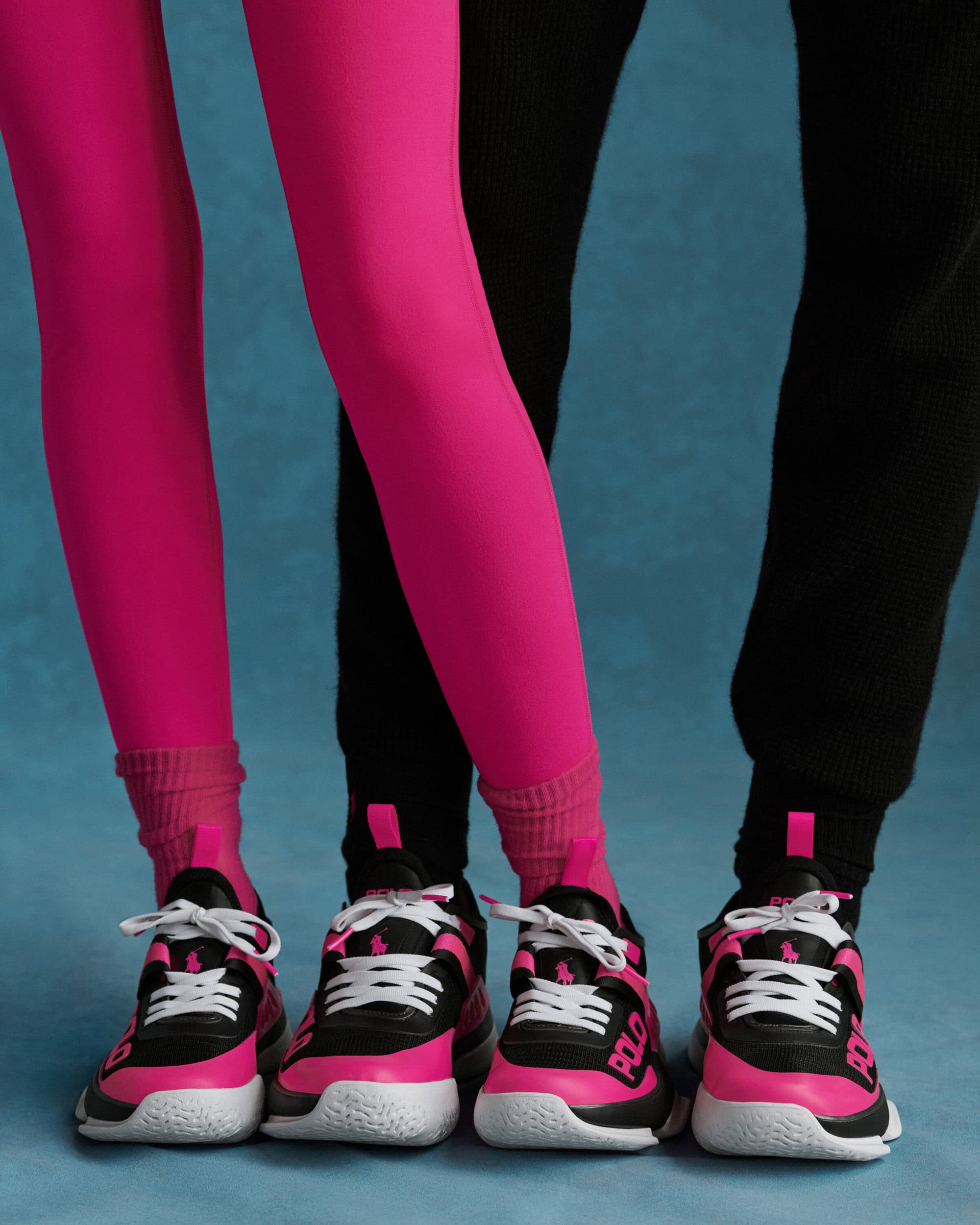 Close-up of four feet wearing black and hot pink sneakers with white laces against a blue textured backdrop.
