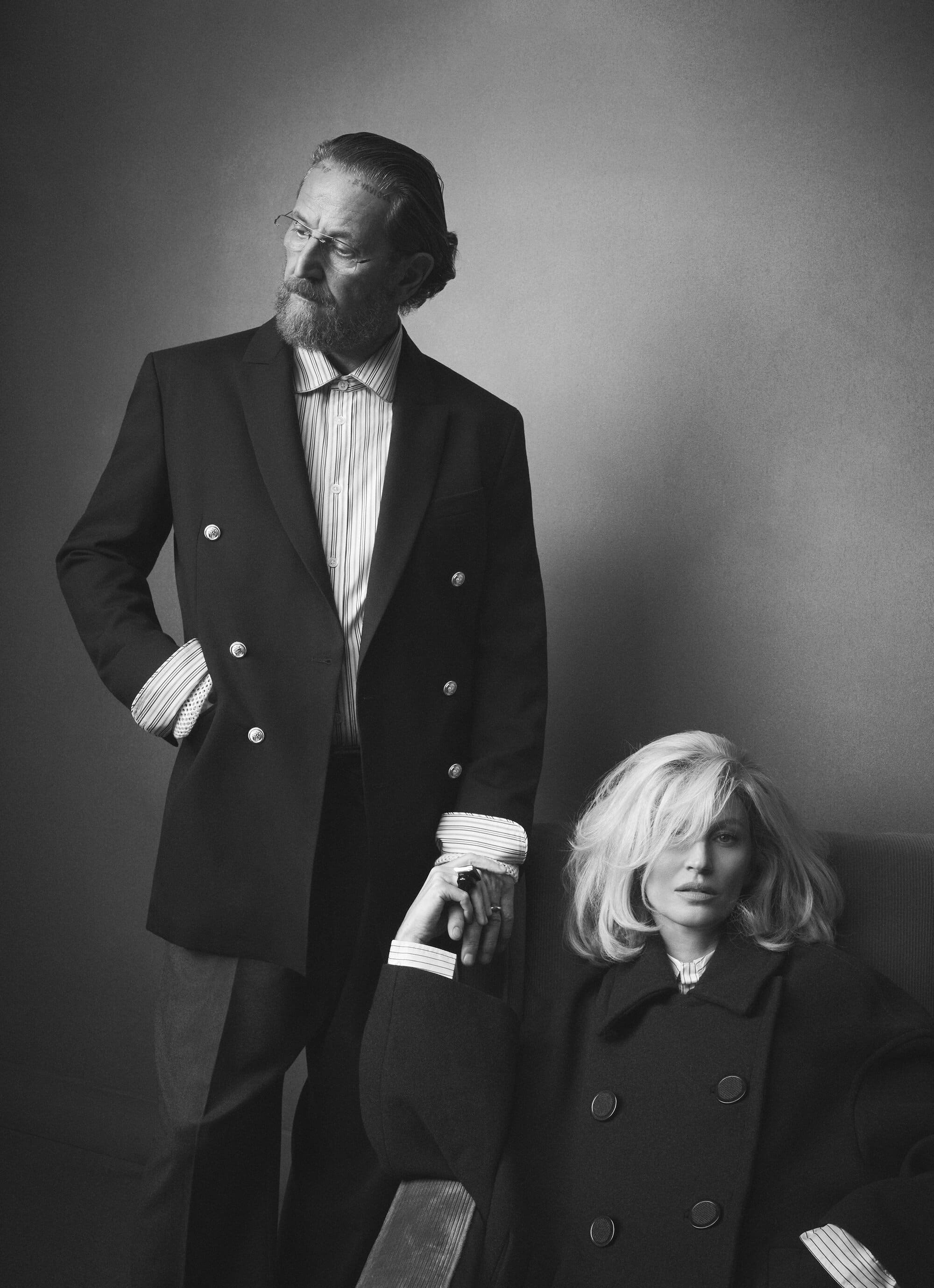 Monochrome portrait of Stefano Pilati standing beside Gisele Bundchen seated in a chair for Zara