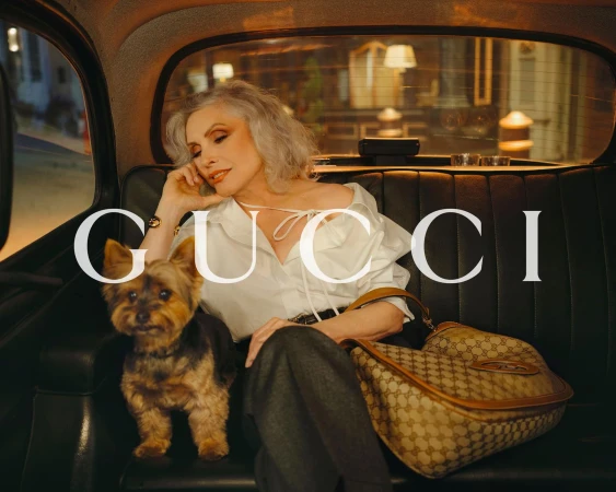 Debbie Harry seated inside a vintage London taxi with a small dog and a monogrammed shoulder bag for Gucci We Will Always Have London campaign