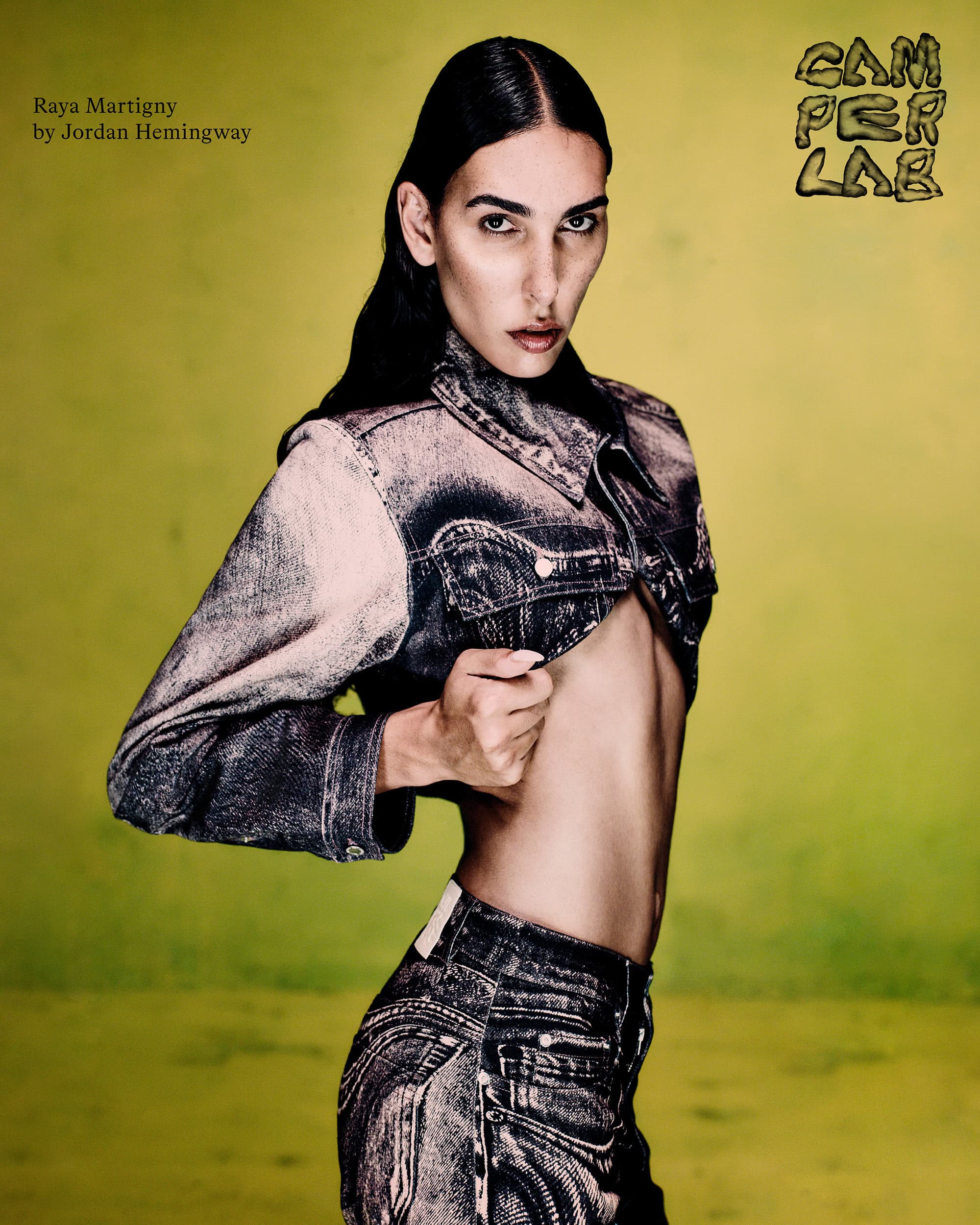 Raya Martigny wearing a cropped acid-wash denim jacket against a textured yellow background for the Camperlab campaign.