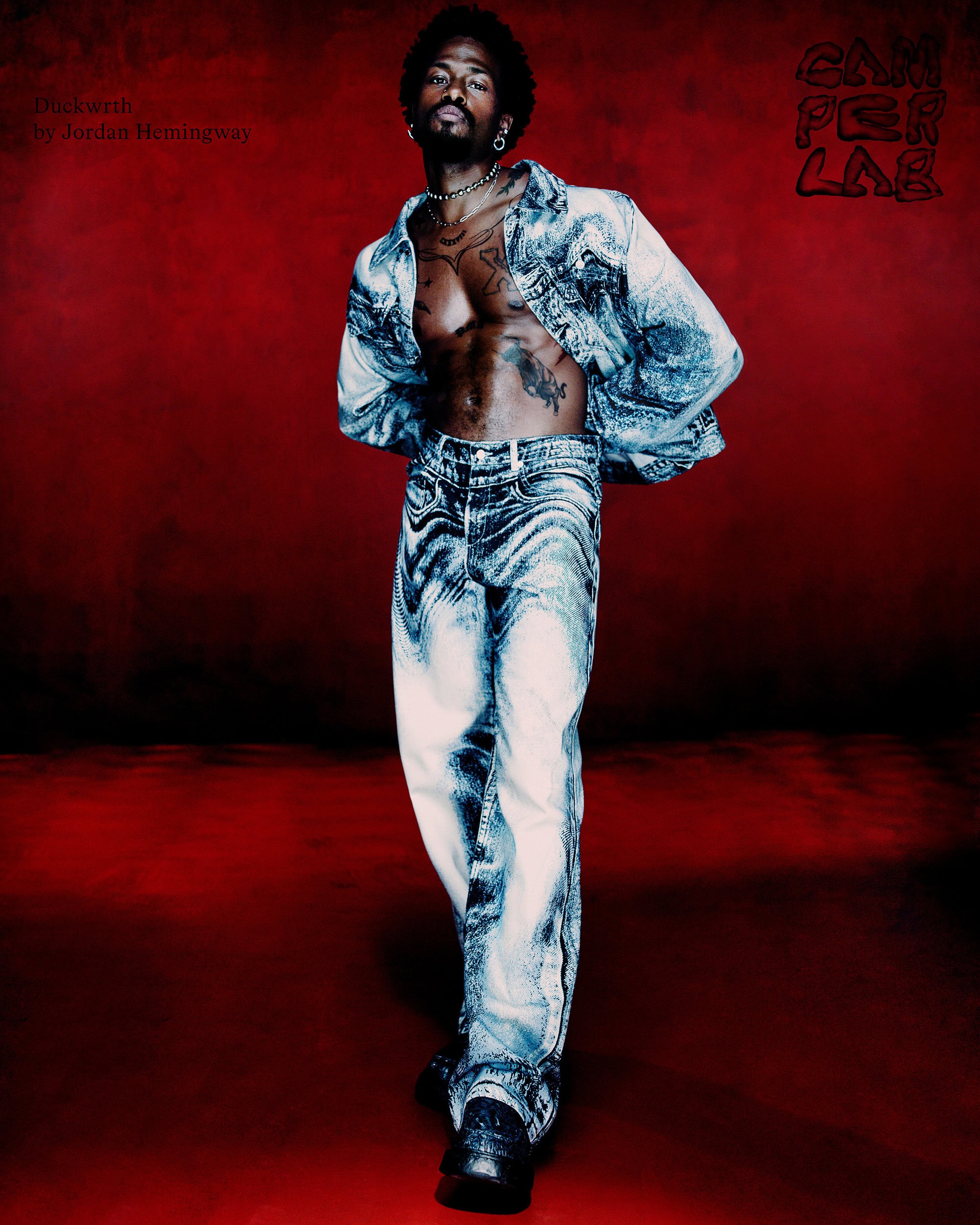 Duckwrth wearing patterned denim set against a deep red background for the Camperlab Fall 2024 campaign, photographed by Jordan Hemingway.