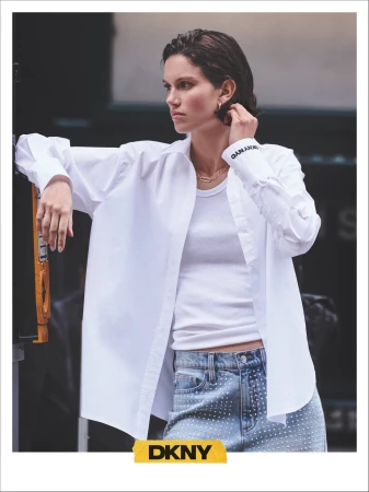 Model Felice Nova Noordhoff wearing a white button-down shirt and denim jeans for the DKNY Fall 2024 campaign.