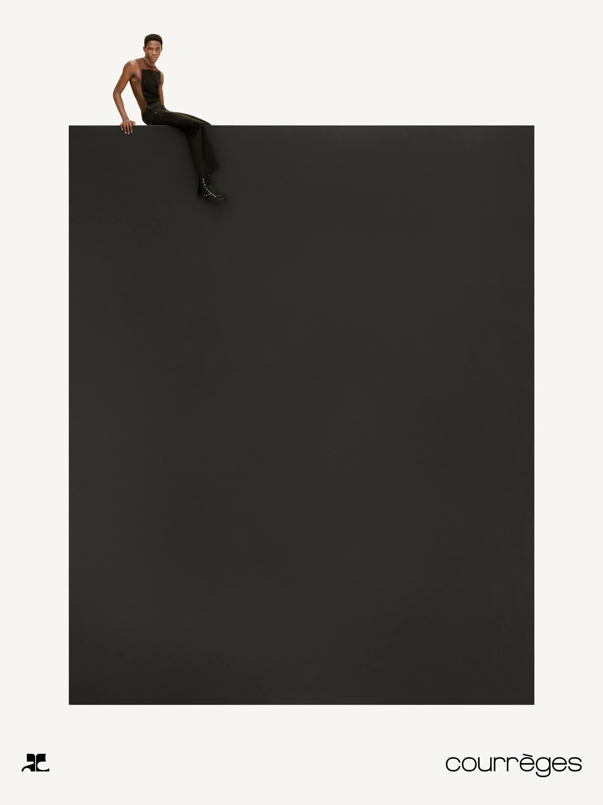 Model sitting on the edge of a large dark block against a white background for Courrèges Fall 2024 campaign