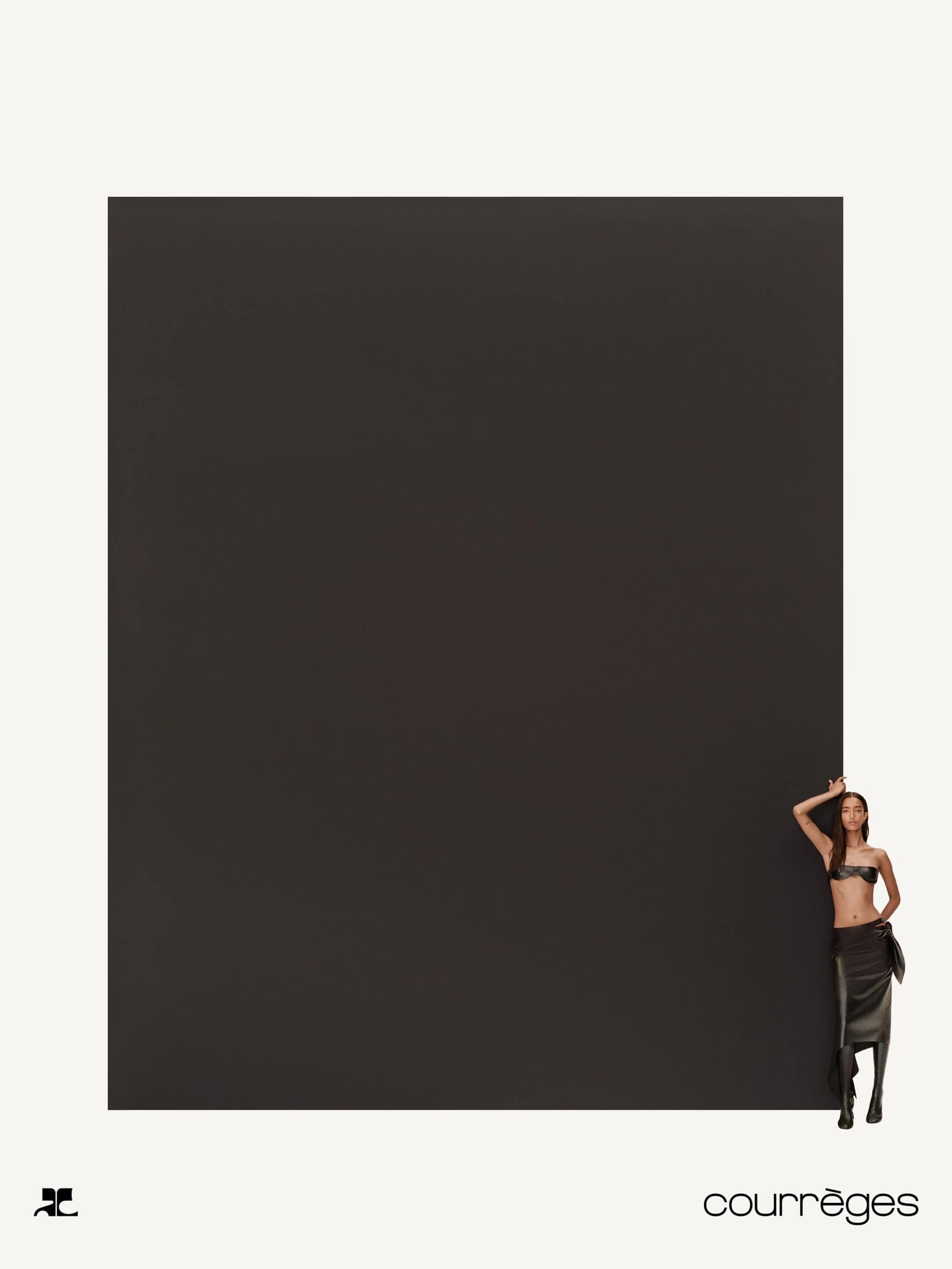Model standing against a massive dark rectangular panel in a minimal white studio setting for Courreges Fall 2024 ad campaign